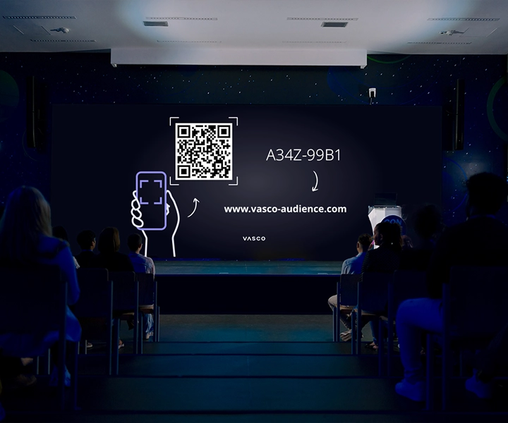 Un grand écran dans la salle de conférence affiche les instructions « Rejoindre Vasco Audience », indiquant aux participants comment accéder à la session.