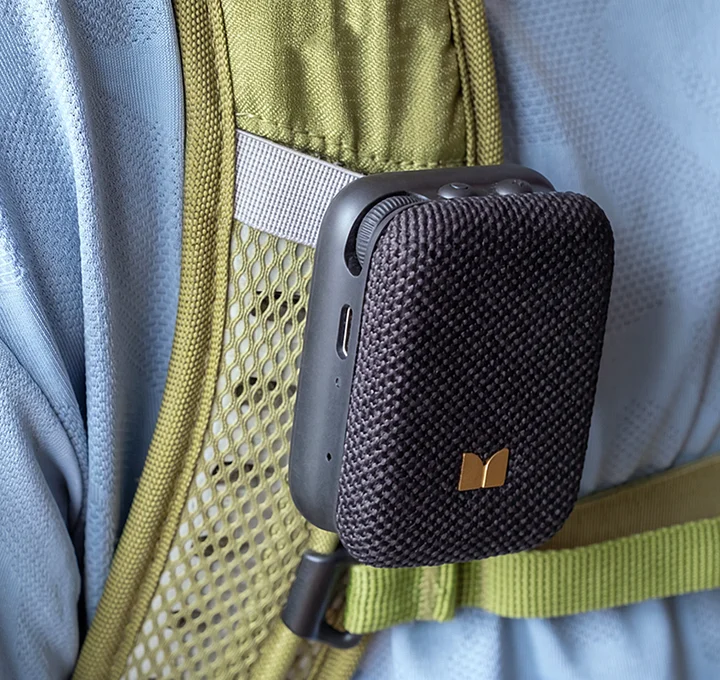 Mini-enceinte Bluetooth noire accrochée à la sangle vert olive d'un sac à dos