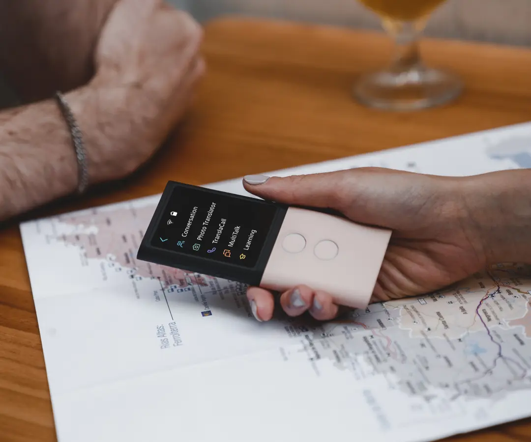 Gros plan sur une main tenant un traducteur au-dessus d’une table, où repose une carte.