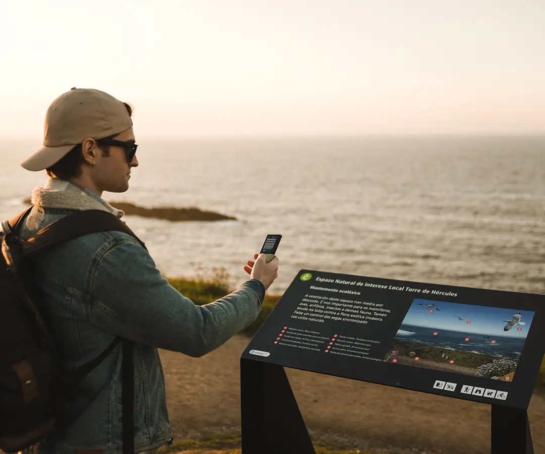 Au bord de la mer, un homme utilise un traducteur photo pour lire un panneau d’informations touristiques sur son emplacement.